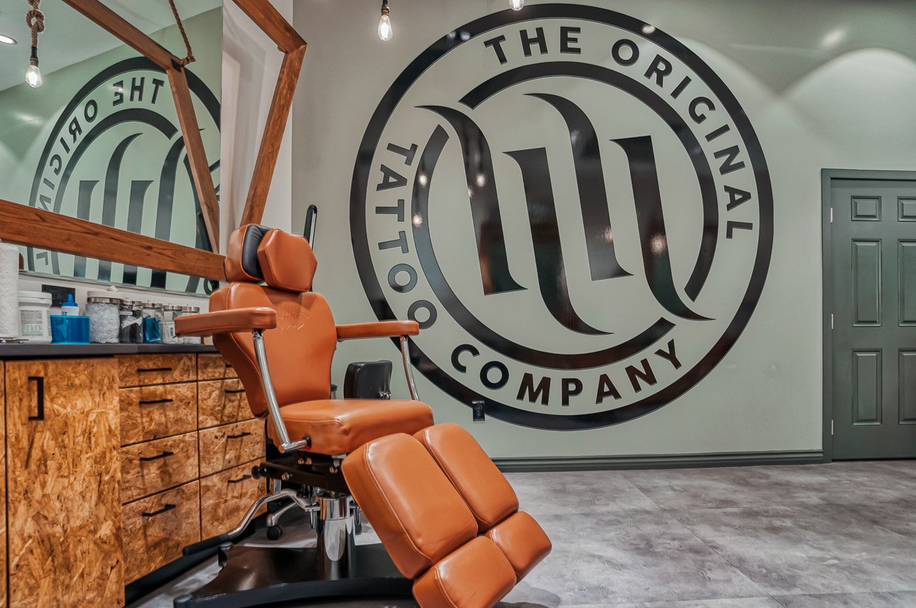 Our tattoo station next to a wall sized H&amp;H logo