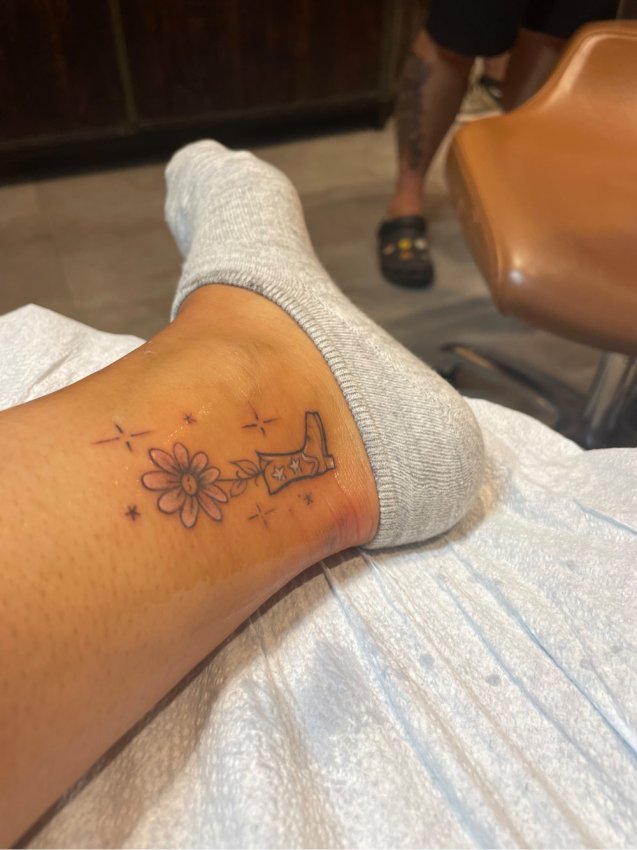 Kelly's tattoo of cowboy boots and a flower